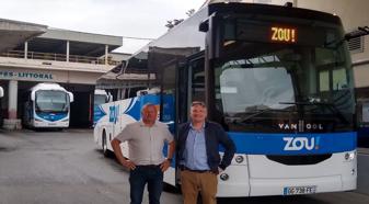 Two men standing in front of blue and white VanHool bus