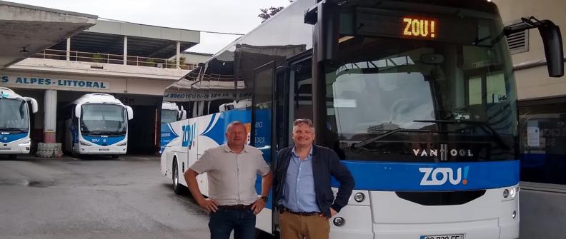 Two men standing in front of blue and white VanHool bus