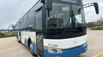 A blue and white bus sits parked in a dirt lot.