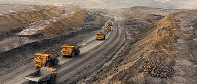 Large quarry dump truck. Big yellow mining truck at work site. Loading coal into body truck. Production useful minerals. Mining truck mining machinery to transport coal from open-pit production.