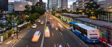Traffic rushes in Jakarta business district along the city main avenue Jalan Thamrin at sunset in Indonesia capital city. The Transjakarta bus system enjoys its own traffic lane to avoid congestion.
