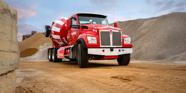 A photo of a red cement mixer truck in a construction work zone.