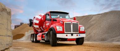 A photo of a red cement mixer truck in a construction work zone.