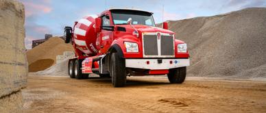 A photo of a red cement mixer truck in a construction work zone.