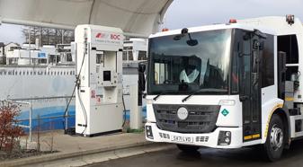 White Hyzon refuse truck in front of fuel pumps hydrogen fuel-cell