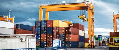 Stack of cargo containers with crane in shipyard.